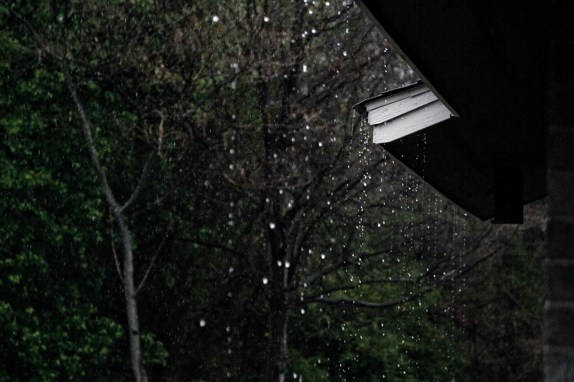Heavy rain pouring over the edge of a rooftop